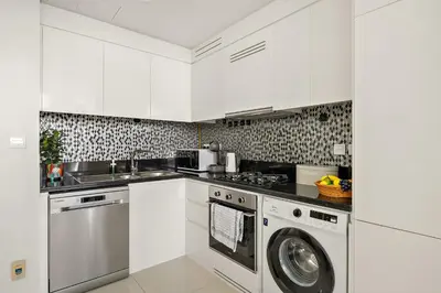 a kitchen with white cabinets and a washing machine at Daniels 2BR with Canal View at Aykon City in Dubai