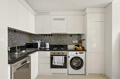 a kitchen with white cabinets and a dishwasher at Daniels 2BR with Canal View at Aykon City in Dubai