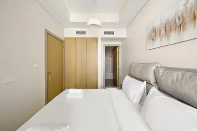a white bedroom with a bed and a couch at Daniels 2BR with Canal View at Aykon City in Dubai