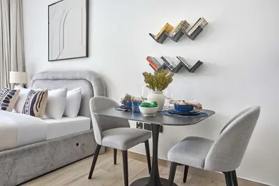 a living room with a table and chairs and a couch at Frank Porter - Oxford Gardens in Dubai