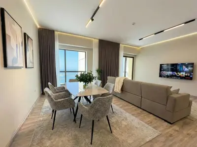 a living room with a couch and a table and chairs at Stunning Sea View - 2-BR - 2 min Walk to Beach in Dubai
