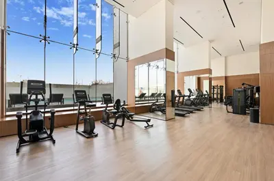 a gym with a row of treadmills and ellipticals at Binghatti House JVC - Parking, Balcony, Gym & Pool in Dubai
