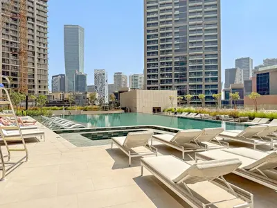 a pool with chaise lounge chairs on a building at FIRST CLASS Studio Relaxing Canal View in Dubai