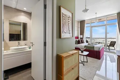a bedroom with a bed and a bathroom with a sink at Stylish Studio with Balcony in Carson Tower, DAMAC Hills in Dubai