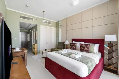 a bedroom with a large bed and a living room at Stylish Studio with Balcony in Carson Tower, DAMAC Hills in Dubai