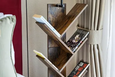 a book shelf with books on it next to a bed at Stylish Studio with Balcony in Carson Tower, DAMAC Hills in Dubai
