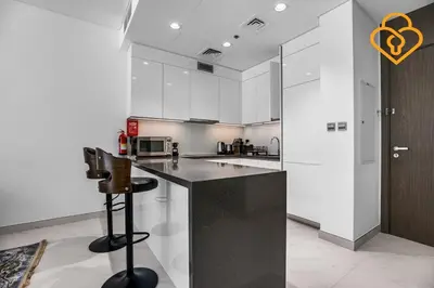 a kitchen with white cabinets and a black counter top at Beautiful Large 1BR Apt in District 1, MBR Minutes to Downtown in Dubai