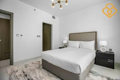 a white bedroom with a large white bed and a window at Beautiful Large 1BR Apt in District 1, MBR Minutes to Downtown in Dubai