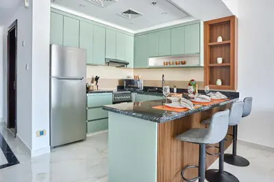 a kitchen with green cabinets and a refrigerator at Frank Porter - Al Rabia Tower in Dubai
