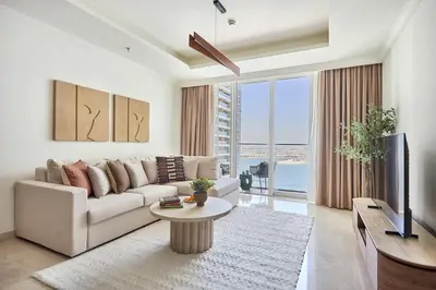 a living room with a couch and a tv and a table at Frank Porter - Palace Beach Residence in Dubai