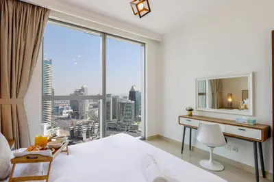 a bedroom with a bed and a desk with a large window at Spacious 1BR with Open Views Boulevard Point Near Dubai Mall in Dubai