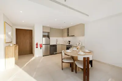 a kitchen with a table and a white refrigerator at Al Jazi 2, Madinat Jumeirah Living - Mint Stay in Dubai