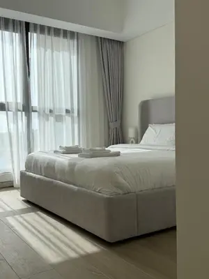 a white bedroom with a large bed in front of a window at Elegant 1BR with Skyline View Bright & Modern by Crescent Key in Dubai