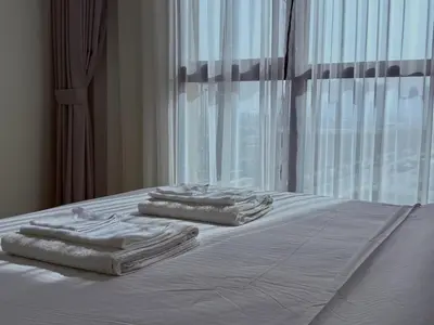 three towels are stacked on a bed with a window at Elegant 1BR with Skyline View Bright & Modern by Crescent Key in Dubai