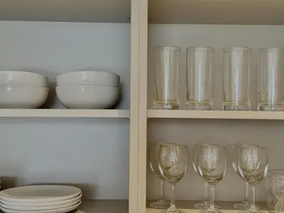 two shelves filled with glasses and bowls and plates at Elegant 1BR with Skyline View Bright & Modern by Crescent Key in Dubai