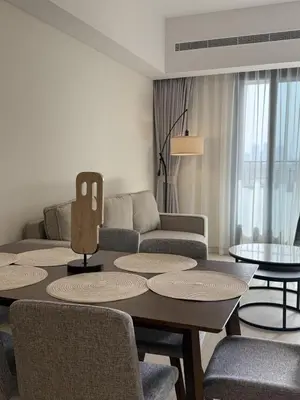 a living room with a table and chairs and a couch at Elegant 1BR with Skyline View Bright & Modern by Crescent Key in Dubai
