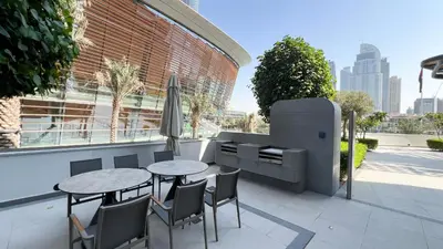 a patio with a table and chairs and an umbrella at INCREDIBLE BURJ KHALIFA & DUBAI FOUNTAIN Views - 2 BR Luxury Apartment - Sanctuary Stays in Dubai