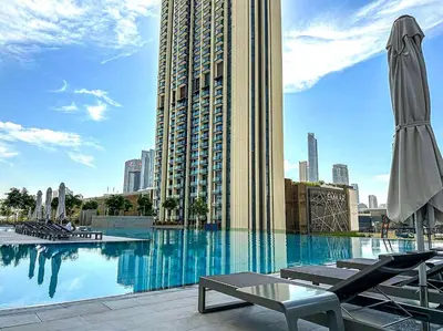 a large swimming pool with chairs and a large building at Luxury Apartment in Burj Vista with Burj Khalifa View in Dubai