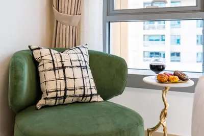 a green chair with a pillow and a glass of wine at Burj Khalifa View 29 Boulevard Downtown - Free Parking in Dubai