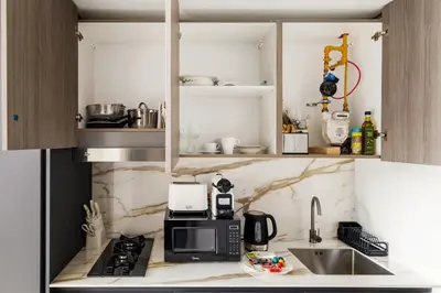 a small kitchen with a sink and a microwave at Chic Studio with Balcony & Pool in Oxford Gardens in Dubai