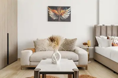 a living room with a couch and a table with a vase at Chic Studio with Balcony & Pool in Oxford Gardens in Dubai
