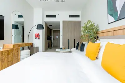 a bedroom with a large white bed with yellow pillows at Nasma Luxury Stays - Contemporary Calm Living Space with upscale Facilities in Dubai