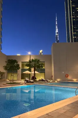 a large swimming pool in a city at night at Premium Downtown 1BD Apartment Burj Khalifa View 9 Mins walk Dubai Mall in Dubai