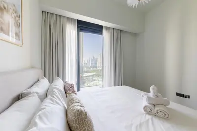a bedroom with a white bed with a large window at Luxury 3BR Burj View in Downtown Dubai in Dubai