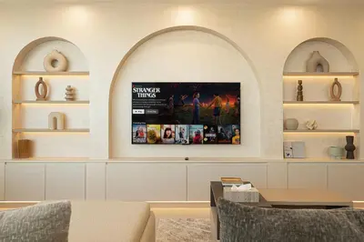 a living room with a tv on a wall with shelves at Elegantly crafted 5 Bedroom with Marina View in Dubai