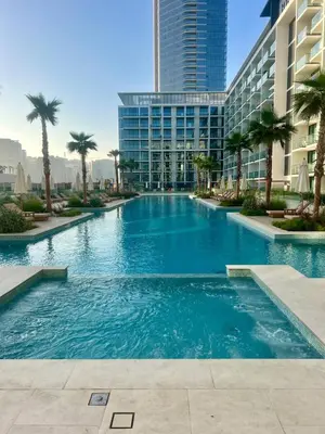 a large swimming pool with palm trees and buildings at Stylish Dubai Stay, Pool, Padel, Gym, Concierge in Dubai