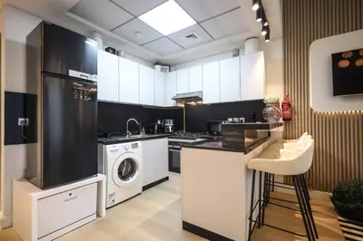 a kitchen with white cabinets and a washer and dryer at Elite LUX Holiday Homes - Cozy Studio at Al Waleed Garden 2, Dubai in Dubai