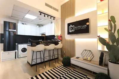 a kitchen with white cabinets and stools in a room at Elite LUX Holiday Homes - Cozy Studio at Al Waleed Garden 2, Dubai in Dubai