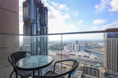 a balcony with a table and chairs in a city at Elite LUX Holiday Homes - Stylish 1BR Living in Amna Tower, Al Habtoor City in Dubai
