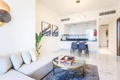 a living room with a white couch and a table at Elite LUX Holiday Homes - Stylish 1BR Living in Amna Tower, Al Habtoor City in Dubai