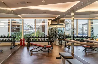 a gym with a lot of exercise equipment and large windows at Elite LUX Holiday Homes - Stylish Studio at Jewelz by Danube, Dubai in Dubai