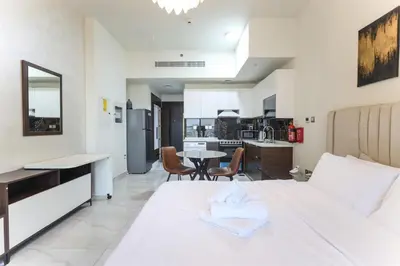 a bedroom with a white bed and a kitchen at Elite LUX Holiday Homes - Stylish Studio at Jewelz by Danube, Dubai in Dubai