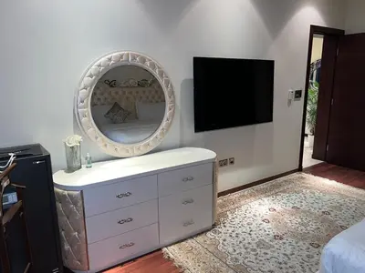 a room with a dresser with a mirror and a tv at Private beach, Close to Shopping Mall in Dubai