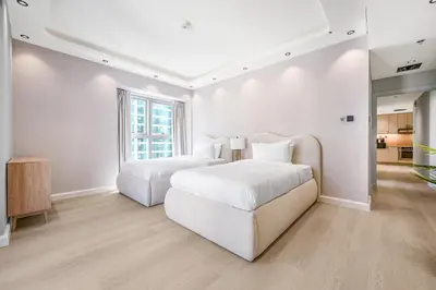 a white bedroom with two beds and a large window at Ample space 2BR Princess towers Marina in Dubai