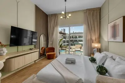 a living room with a large bed and a television at Waves - Modern Studio Retreat W Pool & Gym Access in Dubai