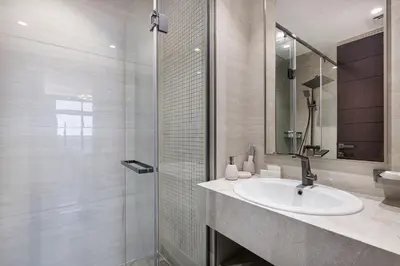 a bathroom with a sink and a glass shower at Nobles Suites By Hostiva in Dubai