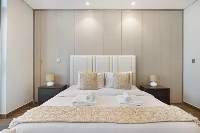 a bedroom with a large white bed with towels on it at Nobles Suites By Hostiva in Dubai