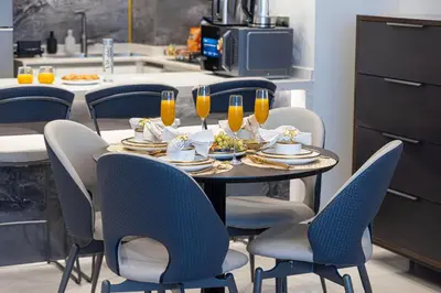 a table with chairs and a table with glasses of orange juice at Nobles Suites By Hostiva in Dubai