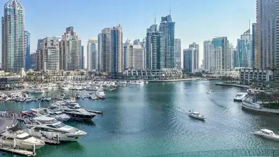 a river with boats in a city with tall buildings at Skyline Marina - Modern 2BR Retreat In Cayan-33 in Dubai