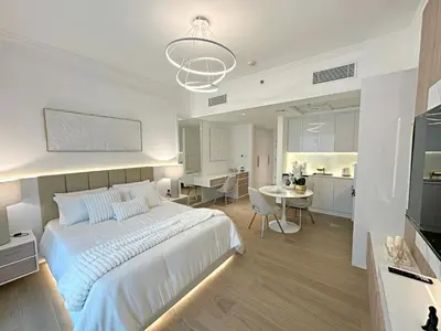 a bedroom with a large white bed and a kitchen at Brand New Studio Downtown, All Bills Included in Dubai