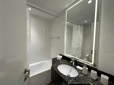 a bathroom with a sink and a mirror and a tub at Brand New Studio Downtown, All Bills Included in Dubai