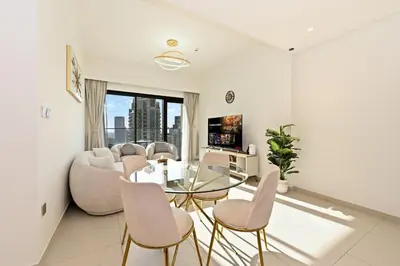a living room with a glass table and chairs at CH Skyline Bliss 1 BR near Burj Khalifa in Dubai