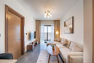 a living room with a couch and a table at Brand New 1 Bedroom Apartment in Sobha Hartland Dubai in Dubai
