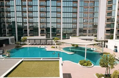 a large swimming pool with a large building in the background at Brand New 1 Bedroom Apartment in Sobha Hartland Dubai in Dubai