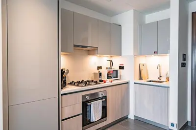 a kitchen with white cabinets and a stove top oven at Brand New 1 Bedroom Apartment in Sobha Hartland Dubai in Dubai