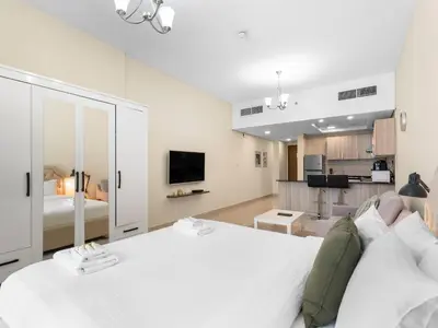a bedroom with a white bed and a living room at The Cozy Corner Studio In Chaimaa in Dubai